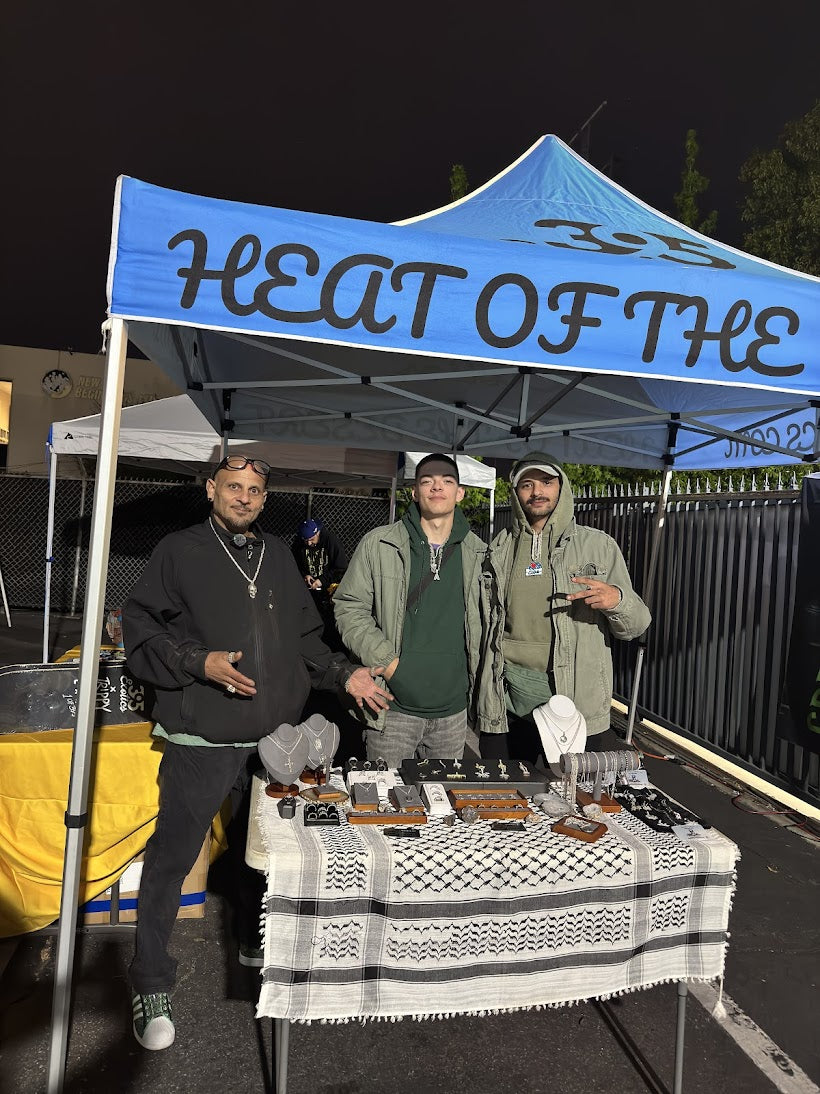 Ali Assi, Miguel and Hector behind a jewelry table under the Heat of the Night tent